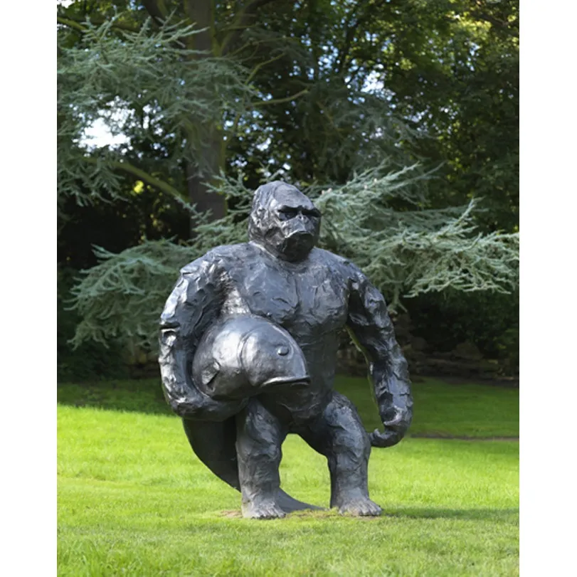 Black Bronze Sculpture Serious Chimpanzee Holds a Fish and Stands on The Lawn